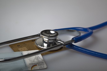 Stethoskop liegend auf einer von zwei abgebildeten Krankenkassenkarten