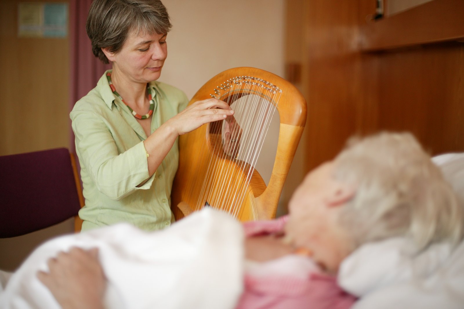 Frau spielt Harfe für Patientin als Musiktherapie